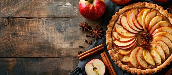 Poster - Close up top view of a homemade fruit tart showcasing golden crust whole and halved apples cinnamon sticks and anise seeds with copy space in the image