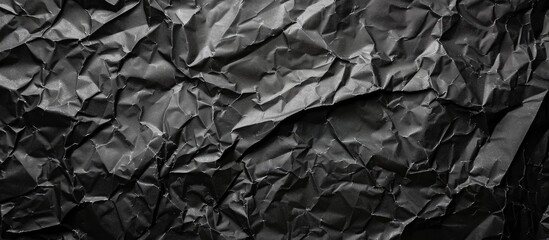 Fototapete - A crumpled black paper background offering texture and copy space image
