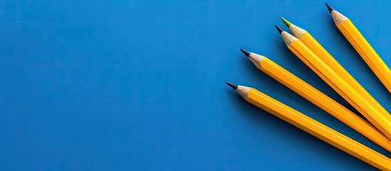 Aufkleber - Aerial view of yellow pencils and blank paper against a blue backdrop with copy space image