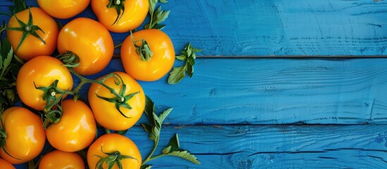Poster - Top view of a blue wooden table adorned with ripe yellow tomatoes providing ample copy space image