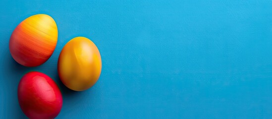Aufkleber - A blue background features three vibrant Easter eggs in red yellow and orange hues providing ample copy space for text within the image