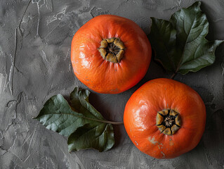 Poster - Two Red Pomegranates With Green Leaves on a Grey Surface