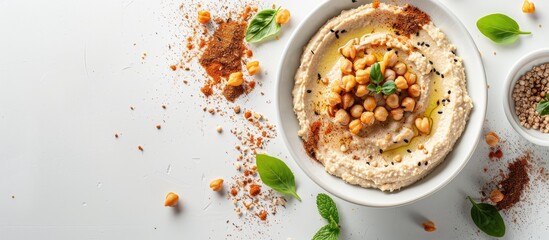 Aufkleber - Top down view of a bowl of hummus surrounded by crispbread crumbs spices and a white background perfect for a copy space image