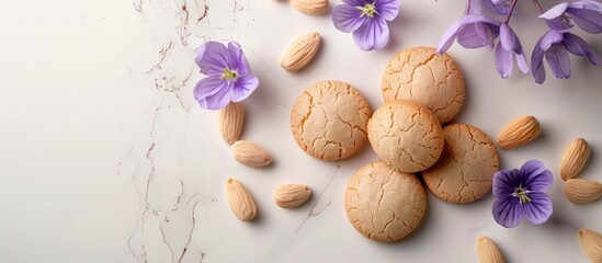 Poster - Almond cookies in pastel colors alongside violet spring flowers on a white background for a copy space image