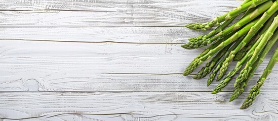 Poster - Close up top view photo of a bunch of fresh asparagus on a white and grey wooden background with empty space for text or other elements. Creative banner. Copyspace image