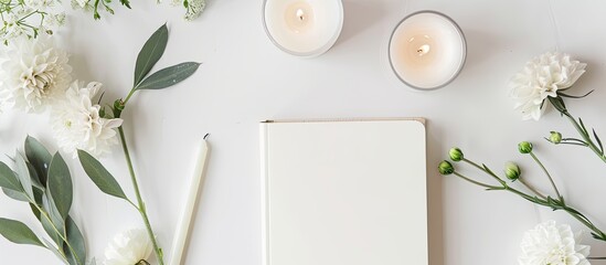Fototapete - From a top down view a flat lay arrangement showcasing a blank notebook a flower and candles on a white surface provides a visually appealing copy space image