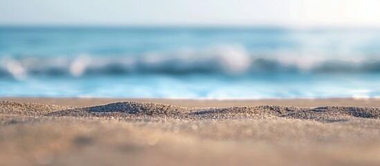 Poster - Blurry ocean background against sand with soft focus showcasing a serene beach scene in a copy space image