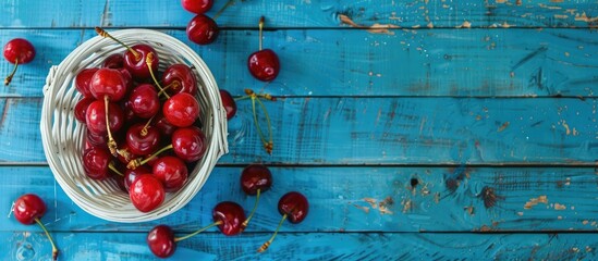 Poster - Cherries placed in a white basket against a blue wooden backdrop in a close up top view with ample copy space for customization in the image