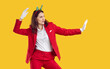 © Studio Romantic - Brunette playful funny woman in hair band with Christmas trees, red suit, white gloves hurrying to Christmas on yellow background. New Year, celebrating winter holidays, Xmas advertisement banner.