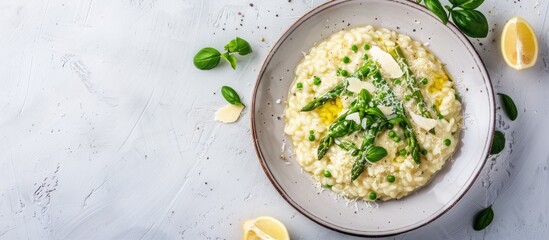 Poster - Top down view of Italian risotto with fresh spring asparagus and parmesan cheese served on a plate against a bright background providing space for additional elements in the image