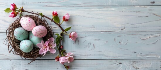 Fototapete - Colorful Easter eggs in a nest with a pink plum flower on a bright white wooden table provide a picturesque copy space image