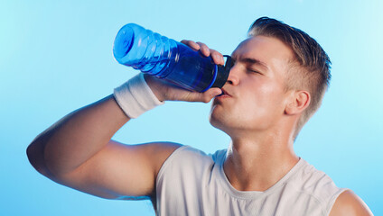 Wall Mural - Man, drinking water and fitness in studio for hydration, health and wellbeing on blue background. Model, bottle and mineral liquid for electrolytes with workout, exercise and training for wellness