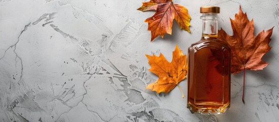 Aufkleber - Flat lay composition featuring a delicious bottle of maple syrup a dry leaf and a light grey table with ample copy space image