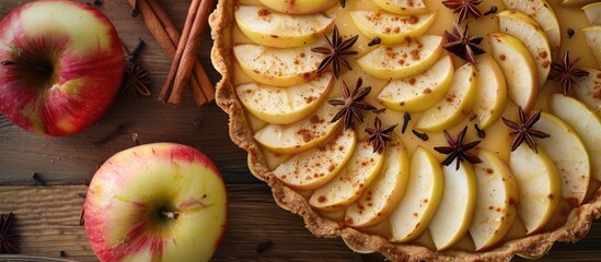 Poster - Close up top view of a homemade fruit tart showcasing golden crust whole and halved apples cinnamon sticks and anise seeds with copy space in the image