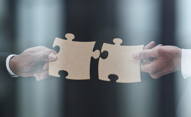 See the big picture. Close-up of an unidentified business man holding two puzzle pieces together.