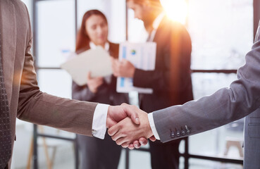 Wall Mural - close-up of a handshake of business partners against the background of colleagues