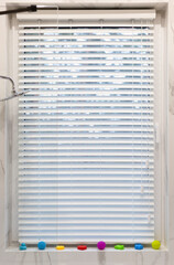Fototapete - White faux wood blinds close up on the window in bathroom, that offer privacy and style. Paired with colorful bath toys. These artificial venetian blinds are not afraid of moisture and water.