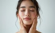 © Onchira - Envisioning a perfect beauty face of a Japanese woman massaging her face on a white background: She has a radiant and flawless complexion, with smooth, glowing skin.