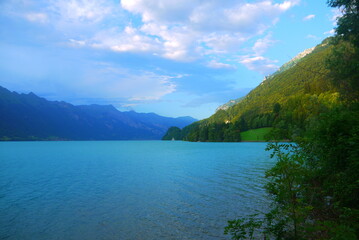 beautiful bright blue lake with grand mountains and clouds in summertime, Switzerland