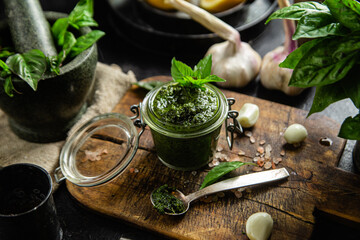 Wall Mural - Green basil pesto sauce in a glass jar on the table