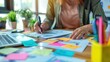 © AGCreative - Person working at desk with colorful sticky notes, papers, and laptop, concept of organization and productivity in modern workspace.
