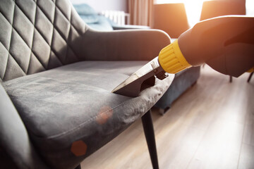 Services for washing and cleaning upholstered furniture with a vacuum cleaner. Cleaning dirty gray chairs in the apartment, industry