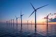 © mariodelavega - A panoramic shot of a row of offshore wind turbines stretching across the horizon at dusk.