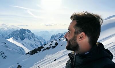 Wall Mural - Handsome young man with beard and mustache standing on top of a snowy mountain and enjoying the view