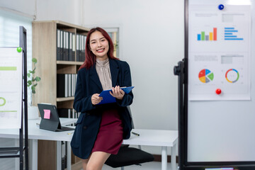 Wall Mural - A woman in a business suit stands in front of a white board with a blue clip in