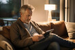 © Olga Miltsova - mature man reading ebook in armchair, leisure concept, Generative AI