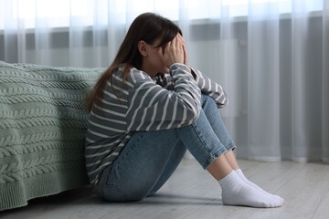 Poster - Loneliness concept. Sad woman sitting on floor at home