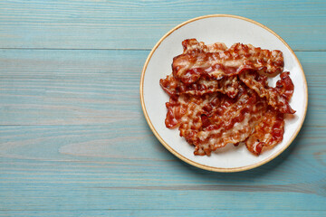 Wall Mural - Slices of tasty fried bacon on light blue wooden table, top view. Space for text