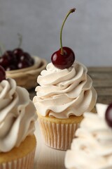 Wall Mural - Delicious cupcakes with cream and cherries on table, closeup