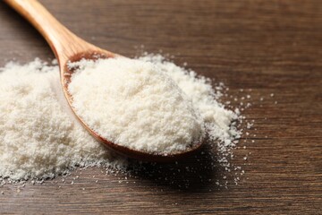 Coconut flour in spoon on wooden table, closeup