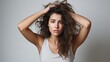 © moumeni - A close-up photograph captures a cute woman wearing a white T-shirt against a white background. She has a pained expression on her face as she places her hand on her forehead.