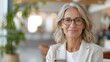 © Lens Legacy - A confident woman with gray hair and glasses is smiling while using her smartphone in a modern setting. The scene highlights the ease and connectivity of contemporary life.