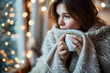 © Eva Corbella - Woman wrapped in a warm blanket, drink hot drinks in a cozy atmosphere in winter.