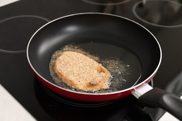 Wall Mural - Cooking schnitzel in frying pan on stove, closeup