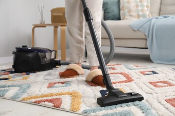 Wall Mural - Woman cleaning carpet with vacuum indoors, closeup