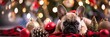 © Elmira - Tiny French Bulldog puppy rests on plaid with Christmas decor, twinkling lights