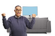 © Ljupco Smokovski - Casual mature man with glasses gesturing happiness in front of tv and sofa