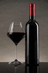 Poster - Bottle and glass with red wine on table against gray background