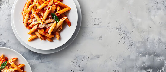 Wall Mural - Top view of penne pasta in red sauce on a white plate against a light grey slate or concrete background, providing a copy space image.