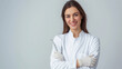 © Maksym - Portrait of a smiling female dentist in a white coat, holding dental tools on a plain light gray background.