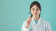 © Maksym - Portrait of a beautiful female scientist in a lab coat, holding a test tube on a plain light blue background.