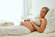 © TamJam/peopleimages.com - Pregnant, woman and portrait with baby toy, expecting mother and maternity leave in house. Gestation, gynecology and family planning for future, belly growth and alphabet blocks for pregnancy on bed