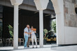 © qunica.com - Group of business professionals having an outdoor meeting, reviewing documents, and discussing strategies in a modern building courtyard.