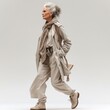 © Vladan - Stylish older woman confidently walking in a chic beige ensemble, showcasing modern fashion for seniors in a contemporary setting.