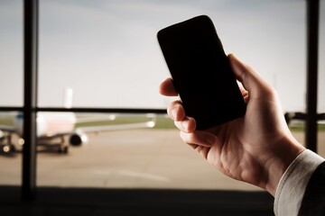 person on the airport, hand holding a smartphone, man using a mobile phone