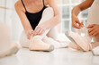 © KayJoint/peopleimages.com - Ballet, shoes and hands of dancers tie ribbon in dance studio, art academy or creative school for practice and training. Students, artist and people on floor getting ready for performance or hobby